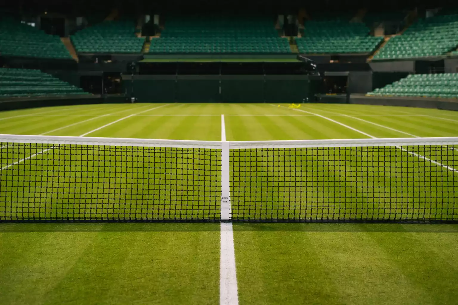 Pista de hierba de Wimbledon con la red en primer plano y las líneas blancas sobre el césped verde impecable del All England Club
