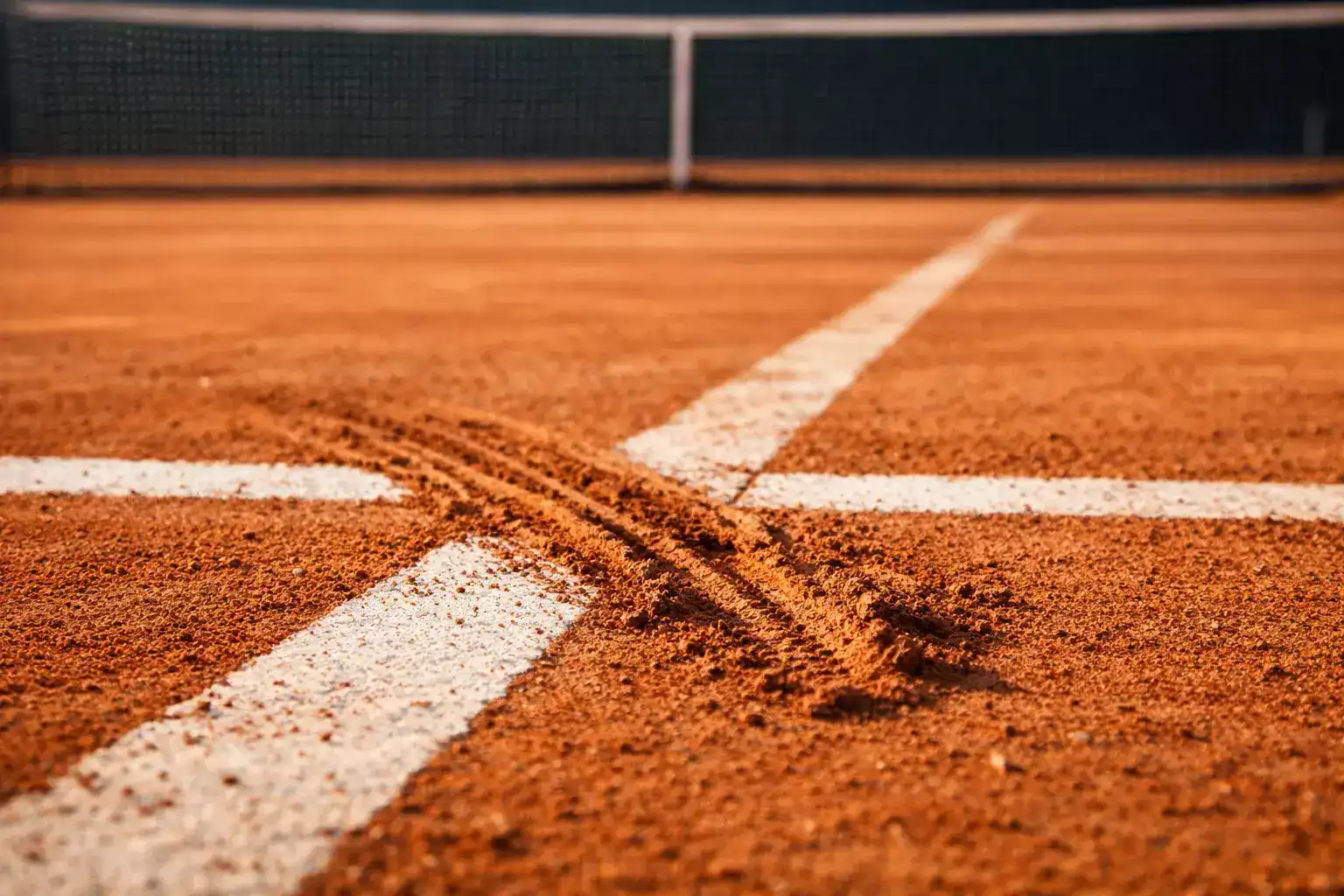 Pista de tenis de tierra batida naranja con líneas blancas y red